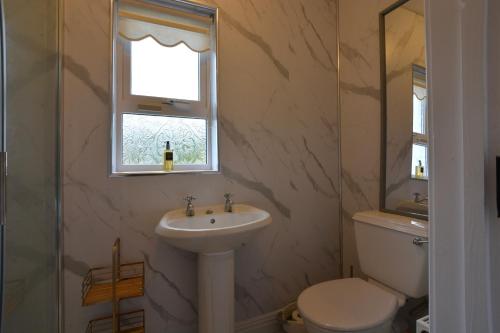 a bathroom with a sink and a toilet and a window at An Grianán Getaway in Burt