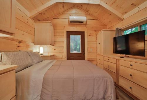 a bedroom with a bed and a flat screen tv at Tiny Cabin Village Private Hot Tub Lynda Cabin in Chattanooga