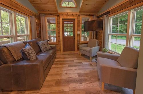 a living room with a brown couch and a tv at Lookout Tiny Cabin 5 Min To Downtown Chattanooga in Chattanooga