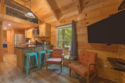 a kitchen with wooden walls and a tv and chairs at Papa Cabin Tiny Log Home Comfort In Rustic Bliss in Chattanooga