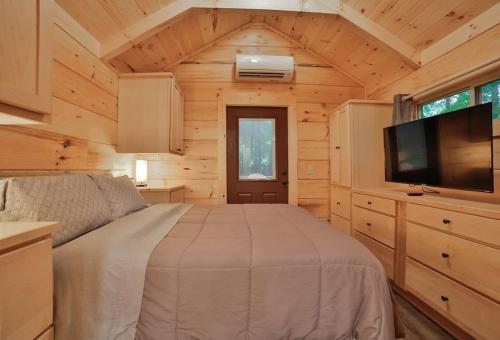 a bedroom in a log cabin with a bed and a tv at Bryce Cabin Lookout Mtn Tiny Home W Swim Spa in Chattanooga