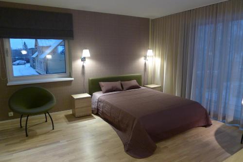 een slaapkamer met een bed, een stoel en een raam bij Liiva Seaside Apartment in Haapsalu