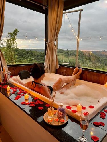 a woman laying in a bath tub with a window at Cabanas Monte Belo in Santa Cruz do Sul