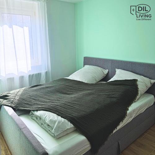 a bed with a black blanket and pillows on it at Modern - zentral - Studio mit Küche - Self Check In in Bad Nauheim