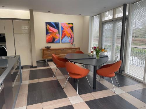 a dining room with a table and orange chairs at Lovely house on the water near Amsterdam in 's-Graveland