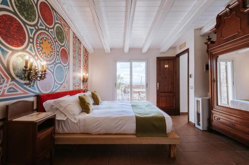 a bedroom with a bed and a wall with a painting at Palazzo Giunta - Porta Marina Ortigia in Syracuse