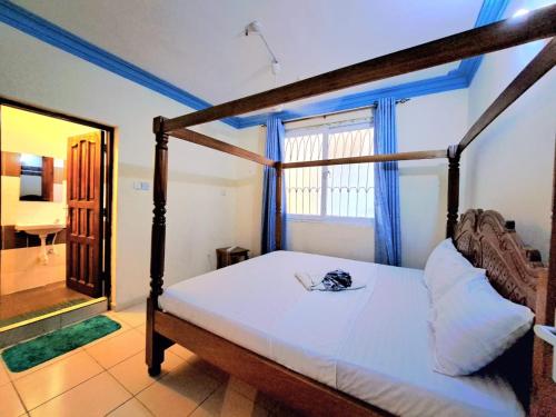 a bedroom with a four poster bed with a mirror at Bamburi Mombasa two bedroom Cutraz homes apartments with swimming pool 005 in Mtwapa
