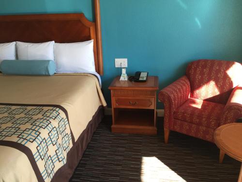 a hotel room with a bed and a chair at Continental Lodge in Oakland