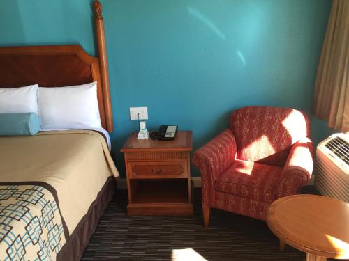 a bedroom with a bed and a chair and a table at Continental Lodge in Oakland