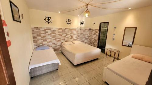 a bedroom with two beds and a tile wall at Hostel-Casa25-Meaipe in Guarapari