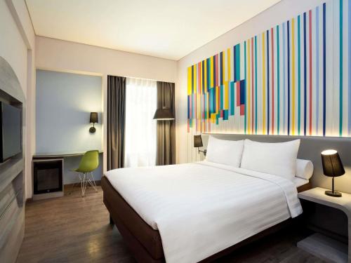 a hotel room with a bed and a painting on the wall at Ibis Styles Jakarta Mangga Dua Square in Jakarta
