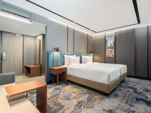 a bedroom with a bed and a table and a couch at Mercure Jakarta Grogol in Jakarta