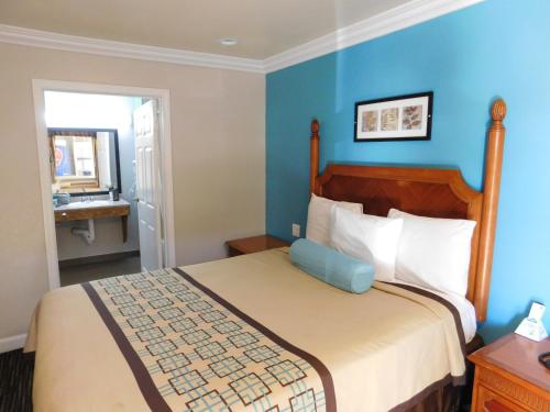 een slaapkamer met een bed met een blauwe muur bij Continental Lodge in Oakland