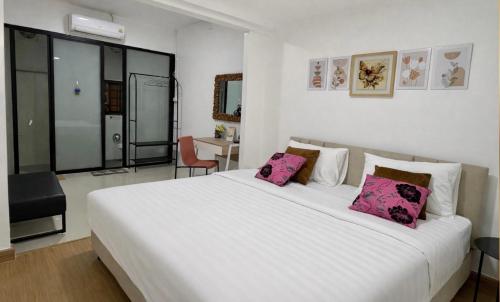 a bedroom with a large white bed with pink pillows at TUK&TOON House in Sathani Ban Thap Chang