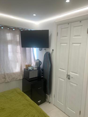 a bedroom with a bed and a flat screen tv at Air Conditioned Modern Double Bed Room with Private Attached Bathroom - FREE Parking - Near London Heathrow Airport & Southall Broadway in Southall