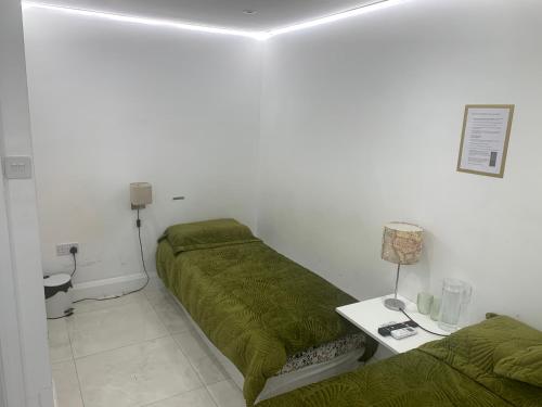 a room with two beds and a table with a lamp at Air Conditioned Modern Double Bed Room with Private Attached Bathroom - FREE Parking - Near London Heathrow Airport & Southall Broadway in Southall