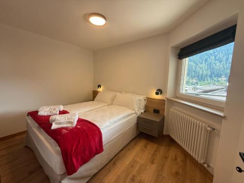 a bedroom with a bed with a red blanket and a window at Al Piz - Dimora Alpina in Pellizzano