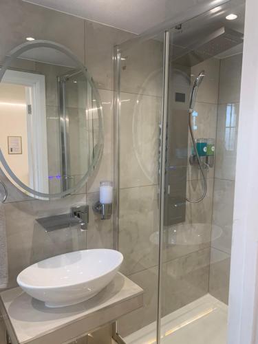 a bathroom with a glass shower with a white sink at Air Conditioned Modern Double Bed Room with Private Attached Bathroom - FREE Parking - Near London Heathrow Airport & Southall Broadway in Southall