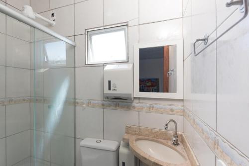 ein weißes Badezimmer mit einem Waschbecken und einem Spiegel in der Unterkunft Pousada Brisa do Mar in Porto Seguro