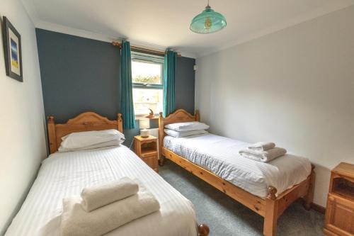 a bedroom with two beds and a window at Tregurrian Villas in Newquay