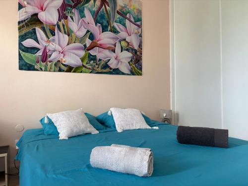 a blue bed with two towels on top of it at Grain de Corail in Saint-François