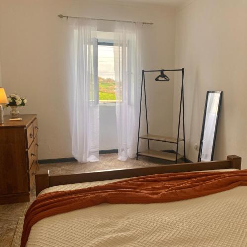 a bedroom with a bed and a window with white curtains at ViladaBaleiaBranca in Remédios
