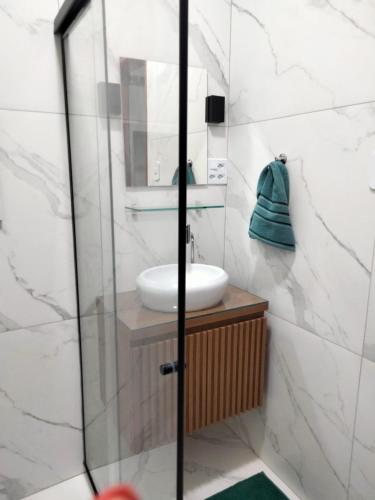a bathroom with a sink and a glass shower at Casa Cordelia Mangaratiba Centro in Mangaratiba