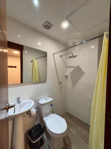 a bathroom with a toilet and a sink and a mirror at Hostal El Recreo in Barranquilla