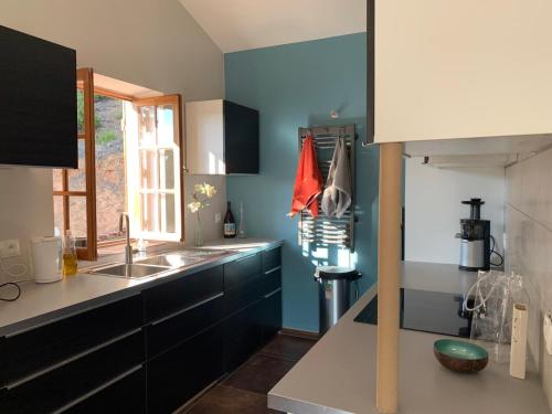 a kitchen with blue walls and a sink and a window at Maison de l'Hermitage in Cucuron