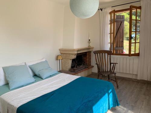 a bedroom with a bed with a fireplace and a chair at Maison de l'Hermitage in Cucuron