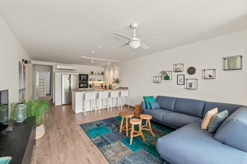 a living room with a blue couch and a kitchen at Blue Bay Apartments in Dorp Sint Michiel