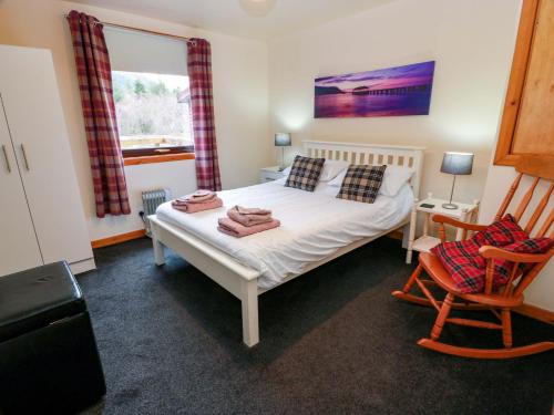 a bedroom with a bed and a chair and a window at Thistle Lodge in Dunoon
