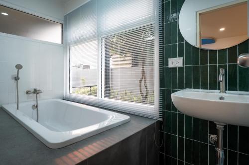 a bathroom with a tub and a sink and a mirror at KYP Hotel โรงแรมขุนยูวเพลส in Fang