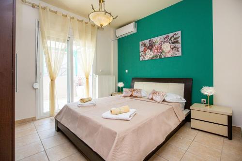 a bedroom with a large bed with a green wall at Villa Aurum in Prinos