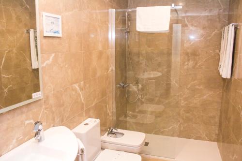 y baño con ducha, aseo y lavamanos. en Hotel Playa Poniente, en Gijón