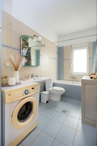 a bathroom with a washer and a toilet and a sink at Villa Aurum in Prinos
