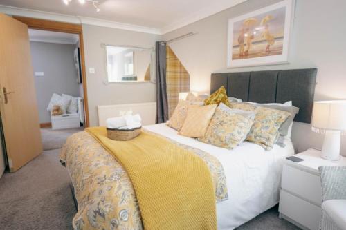 a bedroom with a large bed with a yellow blanket at The Nest - Chandlers in Rothesay