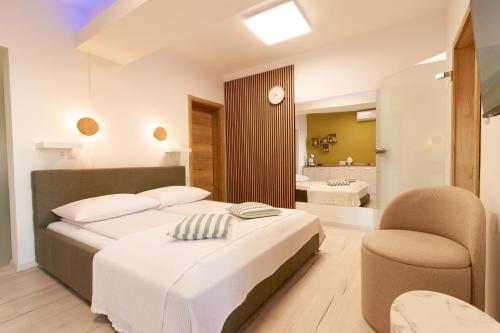 a bedroom with a bed and a chair and a bathroom at Apartmani Enna in Mali Lošinj