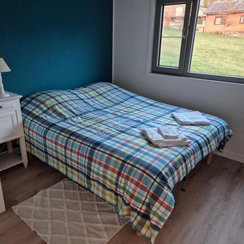 a bed with a plaid blanket and a window at Chalet Les Allores Dohan (Bouillon) in Bouillon