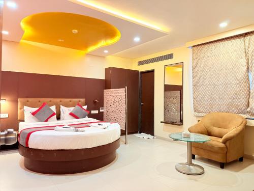 a hotel room with a bed and a chair at Hotel Rajdoot Royale by Ambai in Ichalkaranji