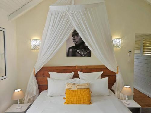 a bedroom with a white bed with a canopy at Bungalow Villa-Déhé in Deshaies