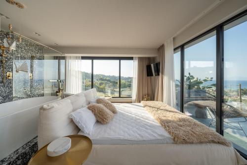 a bedroom with a large white bed and glass windows at Alicanto K1 in Polychrono