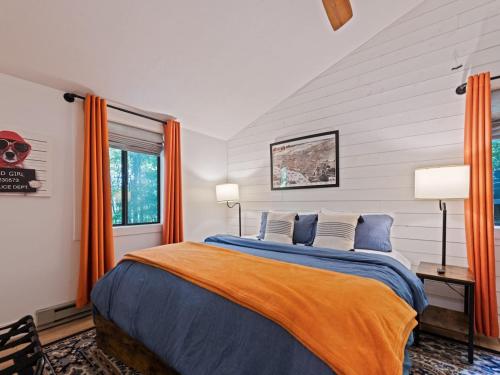 a bedroom with a bed with blue sheets and orange curtains at Kabin Kleighp Maggie Valley in Maggie Valley
