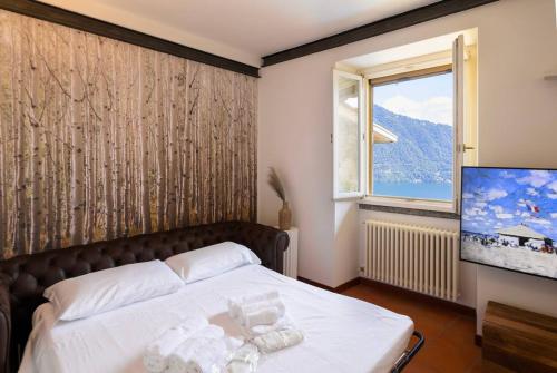 a bedroom with a bed and a tv and a window at Stunning lake view, Cernobbio in Cernobbio