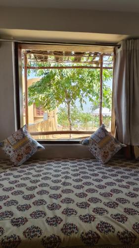a bedroom with a bed and a window with a tree at VVIP Gajban Resort & Desert Stay, Bikaner in Bikaner