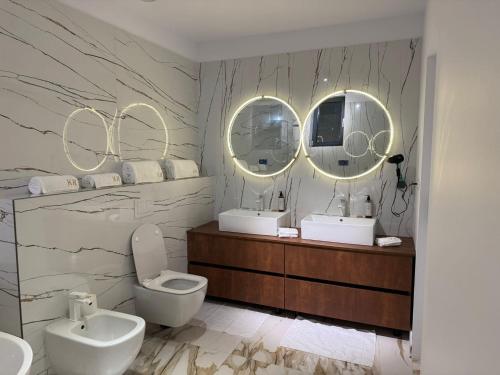 a bathroom with two sinks and a toilet and two mirrors at KNIGHT Villa in Voluntari