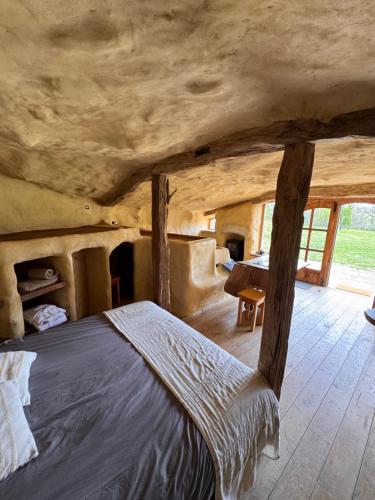 a bedroom with a bed in a room with windows at Maison Terre Les Cabanes de Fallot - sauna bain-froid piscine naturelle in LʼIsle-Bouzon