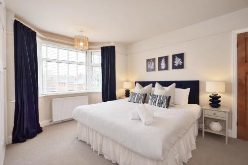 a bedroom with a large white bed with blue curtains at Spacious Gate 3BR City 5mins Walk Pets Welcome in Hereford