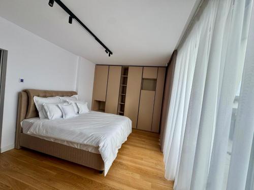 a bedroom with a bed with white sheets and a window at KNIGHT Villa in Voluntari