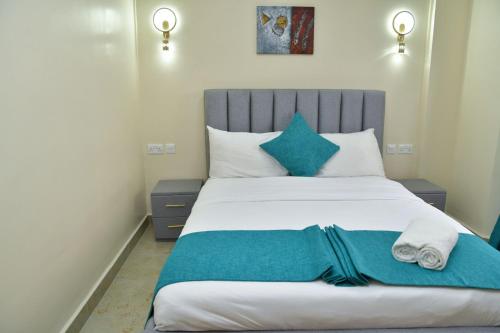 a bedroom with a large bed with blue pillows at Nivaro Homes in Nakuru